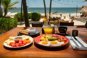 a table with plates of breakfast food on a beach at Ahau Beachfront Tulum Hotel in Tulum