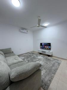 a living room with a couch and a flat screen tv at جوهرة الخوض in Al Khawḑ