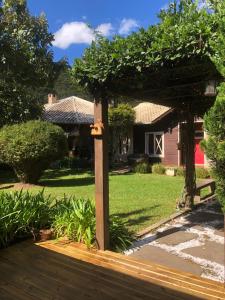 a wooden pergola in a yard with a house at Pousada requinte serrano in Urubici