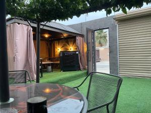 a patio with a glass table and chairs and a yard with grass at دار ناصر in Riyadh