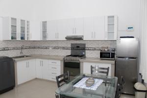 a kitchen with white cabinets and a glass table with chairs at Apartment in Ancon in Ancón