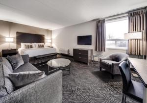 a hotel room with a bed and a couch and chairs at Heritage Inn Hotel & Convention Centre - High River in High River