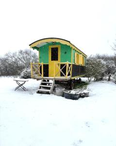 a green and yellow house sitting in the snow at La roulotte MAGIC ! des Grillots in Beaulon