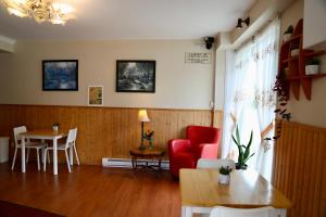 a living room with a red chair and a table at Motel Bel-Eau in Montebello