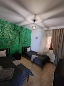 a room with two beds and a green wall at Endless blue apartment kassandra in Nea Fokea