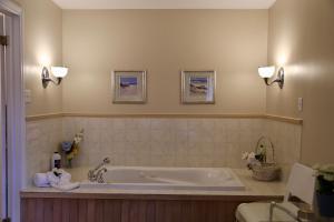 a bathroom with a tub with two lights on the wall at Motel Bel-Eau in Montebello +31 photos