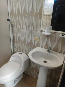 a bathroom with a white toilet and a sink at Iguana Marina House in Puerto Villamil