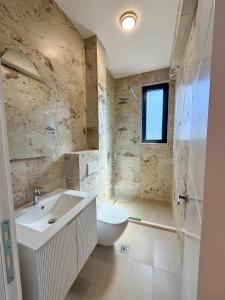 a bathroom with a white toilet and a sink at Maresa 4 in Čanj