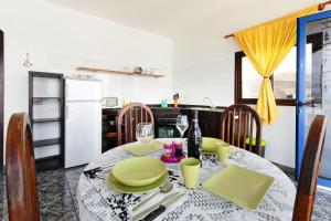 a kitchen with a table with green plates and wine glasses at Caleta Blue House - MacaronesiaHomes in Caleta de Caballo