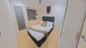 a small bed in a small room with two windows at Canaan Oasis in Pimpama