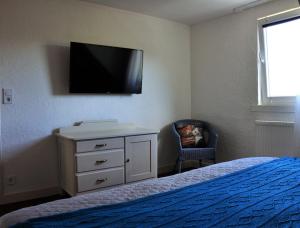 a bedroom with a bed and a dresser with a tv on the wall at Ferienhaus Rosengarten Mürlenbach in Mürlenbach