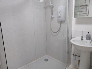 a shower with a glass door next to a sink at Scoor - Garden Cottage in Bunessan
