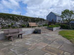 a bench sitting on a patio next to a stone wall at Scoor - Garden Cottage in Bunessan