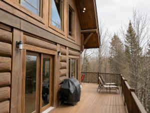 a porch of a log cabin with a grill on it at Belvedere sur le Lac Lodge in Sainte-Adèle