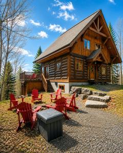 a log cabin with red chairs and a table at Belvedere sur le Lac Lodge in Sainte-Adèle