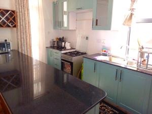 a kitchen with green cabinets and a black counter top at Laneens Apartments in Eldoret