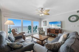 a living room with a couch and a tv and a table at Islander E 7011 Stunning oceanfront condo with pool & gym access in Fort Walton Beach