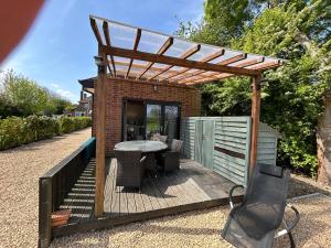 a wooden deck with a table and a pergola at Cobblers Lodge in Somersham +2 photos