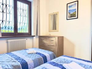a bedroom with two beds and a dresser and a window at Chalet San Primo in Castiglione dʼIntelvi