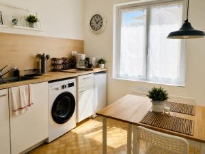 a kitchen with a washing machine and a table at Appartement calme et spacieux - Garage vélo in Saint-Quentin