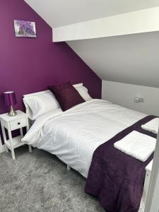a bedroom with a white bed and a purple wall at The Lenton House in Nottingham