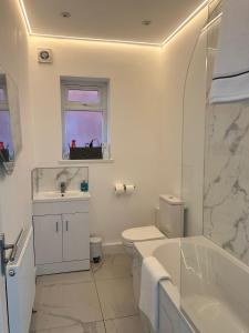 a white bathroom with a sink and a toilet and a tub at The Lenton House in Nottingham +5 photos