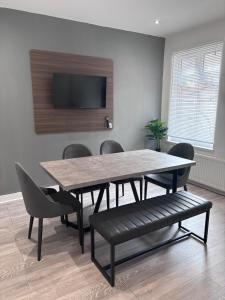 a dining room with a table and chairs and a tv at The Lenton House in Nottingham