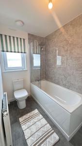 a bathroom with a white tub and a toilet at Gilded Nest-Room with Detached Bath- Ideal for ONE- WIFI, Car Parking-Shared House in Newarthill
