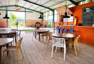a restaurant with tables and chairs and a chalkboard at La roulotte Champêtre des Grillots in Beaulon