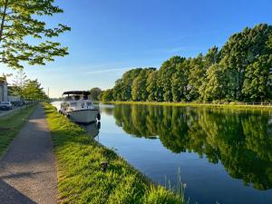 a boat parked on the side of a river at Appartement calme et spacieux - Garage vélo in Saint-Quentin