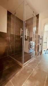 a glass shower in a bathroom with a washing machine at Cozy & small apartment-Böblingen in Böblingen