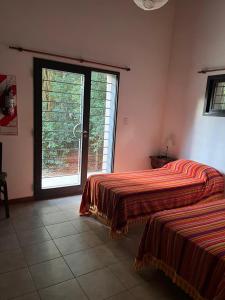 a bedroom with two beds and a large window at El Rincón del Molle in Merlo +10 photos