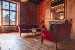 a living room with two chairs and a fireplace at Le Logis d'Equilly in Équilly
