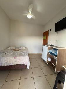 a bedroom with a bed and a flat screen tv at Pousada Nascer da Lua in São Thomé das Letras
