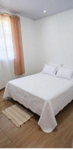 a white bed in a room with a window at Excelente casa com isolamento térmico, dois quarto in Itapoa