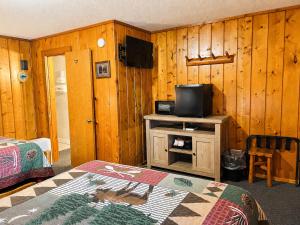 a room with a tv and a bed and a table at Cedars Motel in Saint Ignace