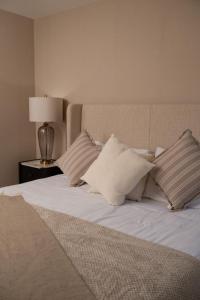 a bed with white sheets and pillows and a lamp at Castlecroft House with Hot Tub in Dungiven