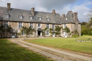 an old stone house with a grass yard at Le Logis d'Equilly in Équilly