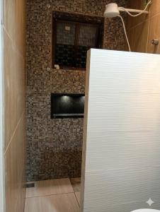 a bathroom with a shower with a brick wall at Excelente casa com isolamento térmico, dois quarto in Itapoa