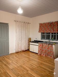 an empty room with a kitchen and a wooden floor at Excelente casa com isolamento térmico, dois quarto in Itapoa