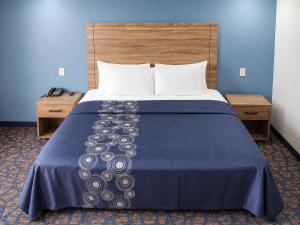a bed in a hotel room with a blue wall at Travelodge by Wyndham Barstow in Barstow