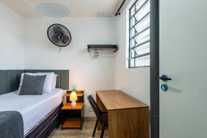 a bedroom with a bed and a desk and a window at Pousada Hostheo liberdade in São Paulo