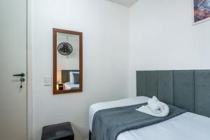 a bedroom with a bed with a mirror and a towel at Pousada Hostheo liberdade in São Paulo