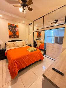 a bedroom with a bed with an orange blanket at Departmento Grande in Puerto Chicama