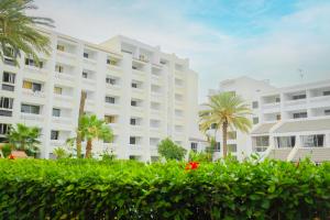a large white building with palm trees in front of it at HAMILTON Agadir in Agadir