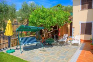 un patio con sillas, una sombrilla y un árbol en Guest House Luciana en Diano Castello