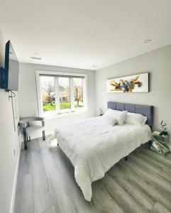 a white bedroom with a large bed and a window at Luxury Nest B&B in Niagara-on-the-Lake