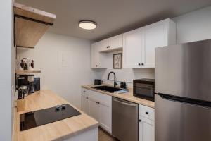 a kitchen with white cabinets and a stainless steel refrigerator at Modern Downtown Studio - King Bed - Inlet Views in Anchorage