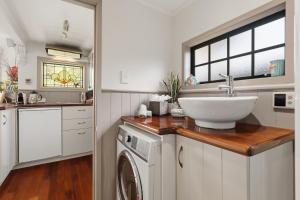 a bathroom with a sink and a washing machine at Private seaside couples hideaway in Kaka Point +25 photos