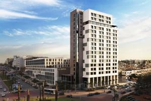 un edificio blanco alto en una calle de la ciudad con coches en The View Rabat, en Rabat